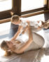 Eine Mutter die mit ihrem Baby Yogaübungen auf einer Decke auf dem Boden macht.